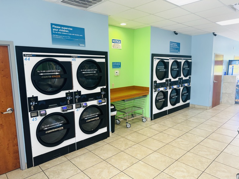 Dryers and a folding station with a rolling laundry cart