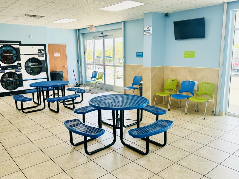 Seating area with tables, chairs and a TV beside the front windows