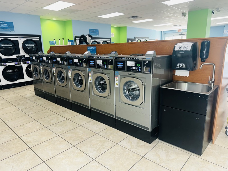 Row of front-load washers beside a stainless utility sink